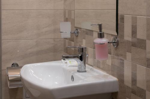 a bathroom sink with a soap dispenser on the wall at Червената къща in Perushtitsa