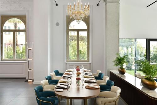 a dining room with a long table and blue chairs at Grand Hotel Victoria concept & spa, by R Collection Hotels in Menaggio