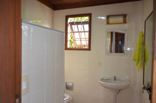 a bathroom with a sink and a toilet and a window at Juquehy a 200m da praia, Wifi, Churrasqueira in São Paulo