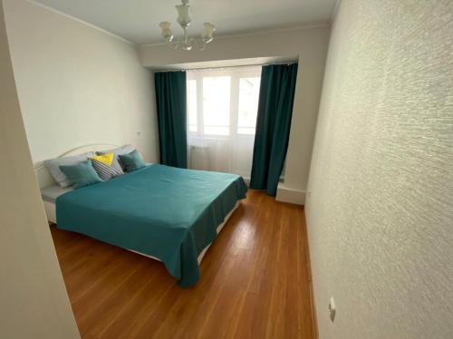 um quarto com uma cama azul e uma janela em Apartments 29 micro-district em Angarsk