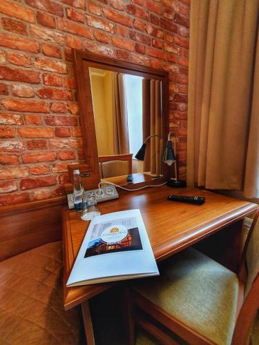 a wooden desk with a mirror and a book on it at Hotel Zamkowy Młyn in Krapkowice