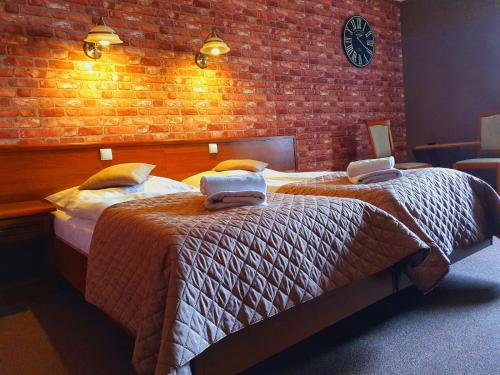 1 dormitorio con 2 camas y pared de ladrillo en Hotel Zamkowy Młyn, en Krapkowice