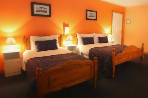 ウェストポートにあるMcCarthy's Lodge B&Bのオレンジ色の壁のホテルルーム内のベッド2台
