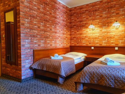 a room with two beds and a brick wall at Hotel Zamkowy Młyn in Krapkowice