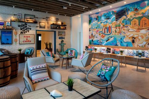 a restaurant with chairs and tables and a large mural at Rove La Mer Beach in Dubai