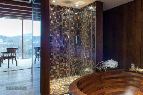 a bathroom with a wooden tub and a glass shower at Vinica Castle Boutique & Spa Hotel in Vinica