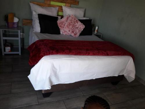 a bed with a red blanket and pillows on it at Lapa la Bakgatlha in Soweto