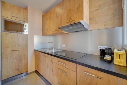 une cuisine avec des armoires en bois et un évier dans l'établissement Immogroom- Sublime studio with terrace- close ShopsBar, à Cannes