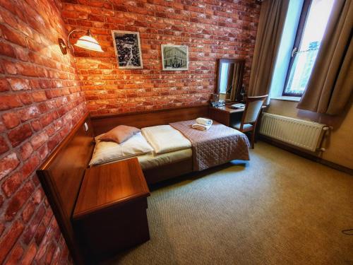 a bedroom with a bed and a brick wall at Hotel Zamkowy Młyn in Krapkowice