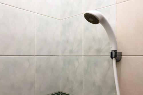 a shower head attached to a white tiled wall at SAS Guest House Mitra RedDoorz At Darmo Park 2 Surabaya in Surabaya
