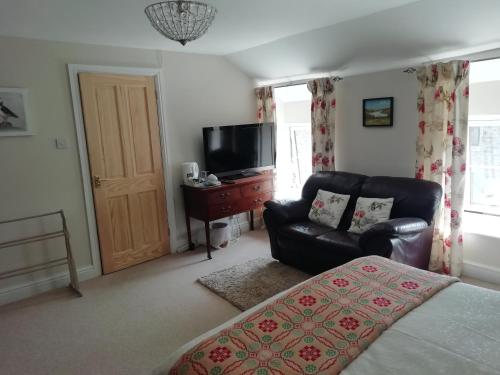 a living room with a bed and a couch and a television at Rectory Farm in Haverfordwest