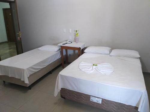 two beds in a room with a nightstand and two beds sidx sidx sidx sidx at Roda Viva Park Hotel in Jales