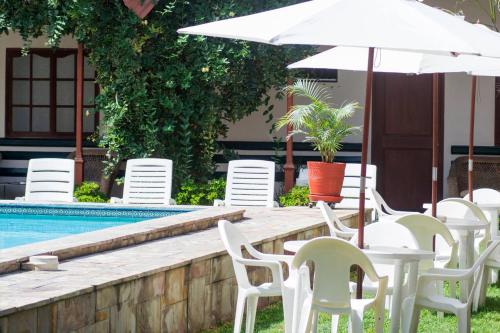 a table with chairs and an umbrella next to a pool at Hotel La Villa Mollendo in Mollendo