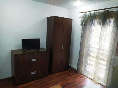 a bedroom with a tv and a dresser and a window at Complex Adela Transfăgărășan in Cîrţişoara