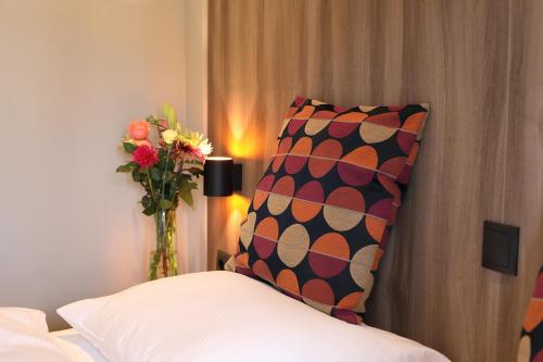 a bedroom with a pillow and a vase of flowers at Hotel Botterweck in Valkenburg