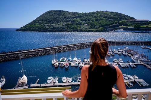 a woman standing on a balcony looking at a marina at Mid-Atlantic Boutique Hostel in Angra do Heroísmo