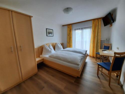 Schlafzimmer mit einem Bett, einem Tisch und einem Fenster in der Unterkunft Pension Aberger in Saalbach-Hinterglemm