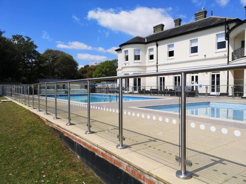 a fence around a swimming pool in front of a house at Mudeford Beach Lodge in Mudeford