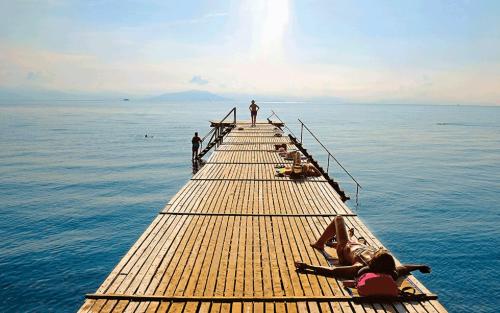 een groep mensen op een pier in het water bij The Bluehouse - Spacious top floor flat with parking, by Mon Repos beach in Corfu-stad