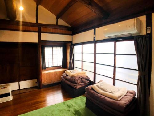 a living room with two couches and a large window at Guesthouse Yadocurly in Onomichi