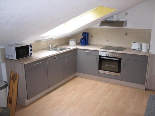 a kitchen with a sink and a microwave at Ferienwohnungen - An der Kunstakademie in Heimbach