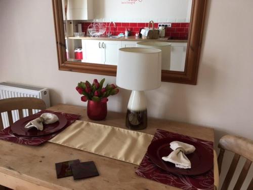 a table with two plates and a lamp and a mirror at Apartment One in Beer