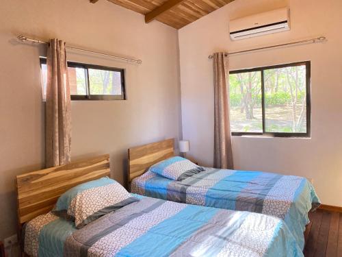 two beds in a room with two windows at CASA NATURaL in Brasilito