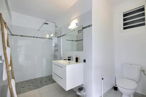 a white bathroom with a toilet and a sink at Lodge du piton à Ste-Anne, lodge de charme, 1 chambre, Jacuzzi, 10 minutes des plages in Sainte-Anne