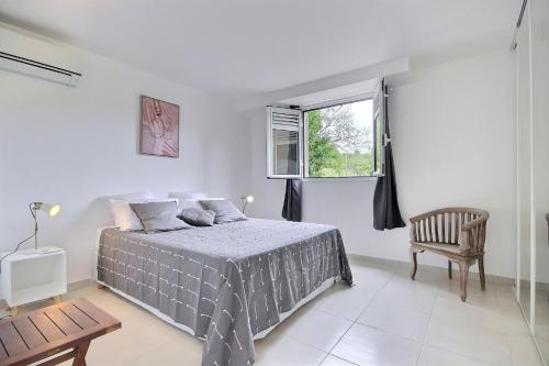 a bedroom with a bed and a chair and a window at Lodge du piton à Ste-Anne, lodge de charme, 1 chambre, Jacuzzi, 10 minutes des plages in Sainte-Anne