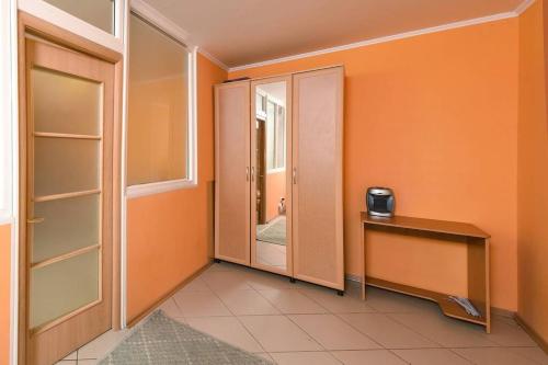 a hallway with orange walls and a table and a mirror at Двухкомнатная посуточно на проспекте К-Маркса, 30 in Omsk