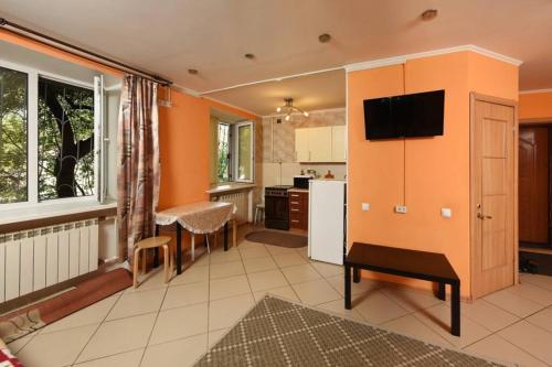 a kitchen with an orange wall with a flat screen tv at Двухкомнатная посуточно на проспекте К-Маркса, 30 in Omsk