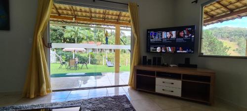 a living room with a tv and a large window at Casa Amarela da Uruçu in Aracê