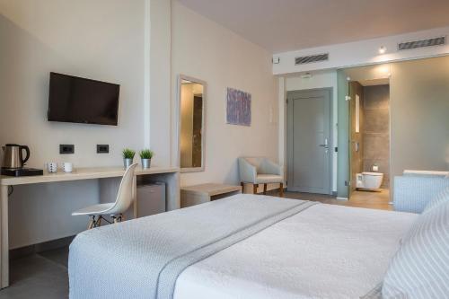 a bedroom with a bed and a desk and a television at ASTRA Village Resort in Svoronata