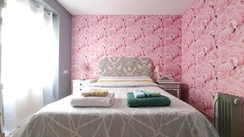 a pink bedroom with a bed with two pillows on it at Hostal Martes Cáceres Plaza Mayor - Tercer piso SIN ascensor in Cáceres