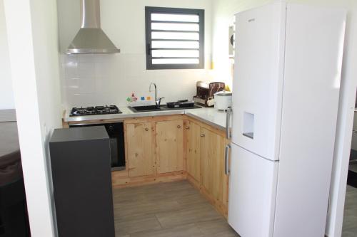 La cuisine est équipée d'un réfrigérateur blanc et de placards en bois. dans l'établissement l'an dormi vacances, à La Plaine des Cafres