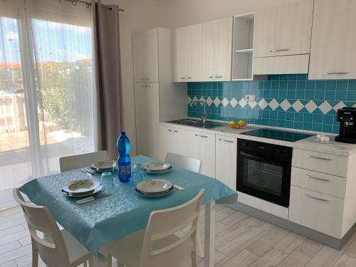 a kitchen with a table with a blue table cloth on it at Le ciliegie: appartamento moderno Isola Rossa in Isola Rossa