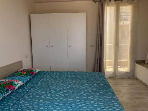 a large bed in a room with a large window at Le ciliegie: appartamento moderno Isola Rossa in Isola Rossa