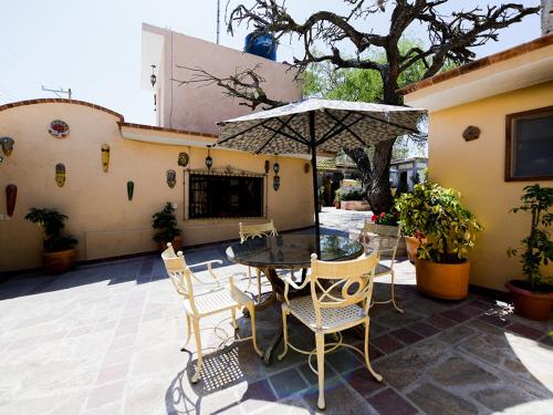 a patio with a table and chairs and an umbrella at Posada Las Reynas by Rotamundos in Mineral de Pozos