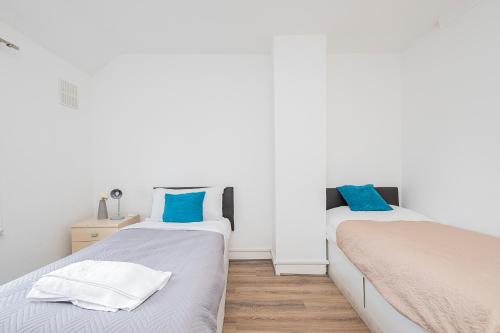 two beds in a room with white walls and blue pillows at Dagenham Self catering House for Larger Groups with Free Parking in Dagenham