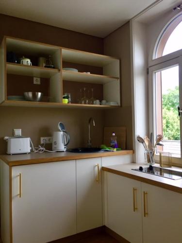 a kitchen with white cabinets and a sink and a window at "goethezimmer" - auf dem Dach der NOTENBANK in Weimar