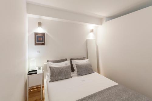 a white bedroom with a bed with two pillows at BO - Almada in Porto