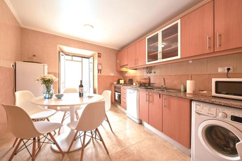 a kitchen with a table and chairs and a microwave at Idyllic Lisbon Apartments With Amazing Courtyard, By TimeCooler in Lisbon