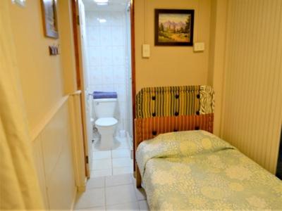 a small bathroom with a bed and a toilet at Hostal Mi Maravilla in La Serena