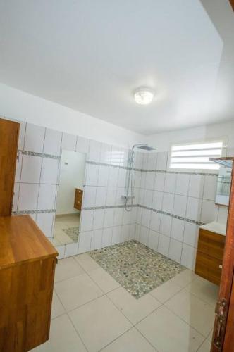 a bathroom with a shower with white tiled walls at Maison accueillante avec piscine partagée à Anse-Bertrand in Anse-Bertrand