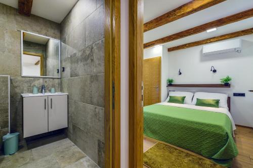 1 Schlafzimmer mit einem grünen Bett und einem Badezimmer in der Unterkunft Urban Apartments with sauna in Zadar