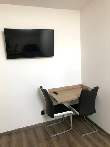 a desk and a chair with a television on a wall at Ubytování Osové in Velké Meziříčí