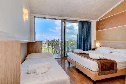 a hotel room with two beds and a balcony at Hotel Rivus in Peschiera del Garda