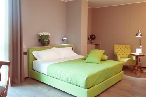 a bedroom with a green bed and a chair at H2C Hotel Milanofiori in Assago