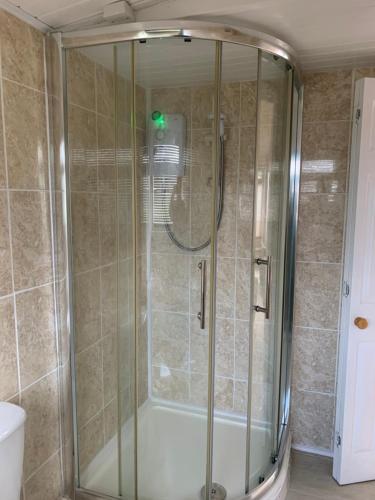La salle de bains est pourvue d'une douche avec une porte en verre. dans l'établissement Dartmouth 2 Bed Detached Chalet Number 144, à Dartmouth