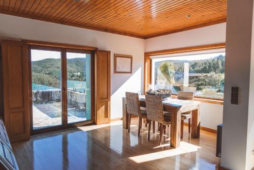 a dining room with a table and chairs and large windows at Casa das Santiagas em Arouca in Arouca